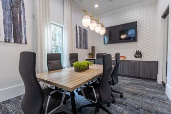A conference room with a wooden table and black chairs.